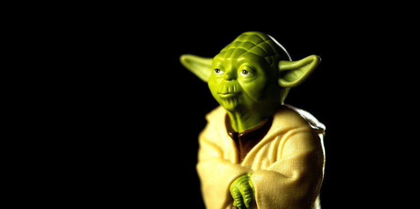 Image of Yoda standing with his arms folded against a black background.