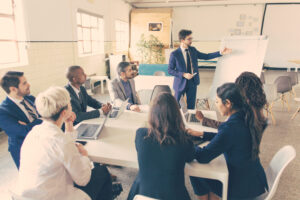 Confident business team working at office. Group of workers sitting at table and listening speaker. Business meeting concept