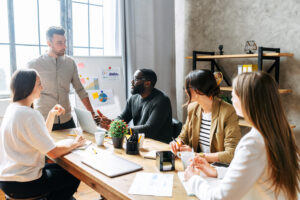 Successful team of startupers in contemporary office is discussing current issues. A multiracial team gathered at the table in contemporary office.