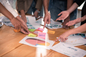 Hands of six people on meeting table point and brainstorming