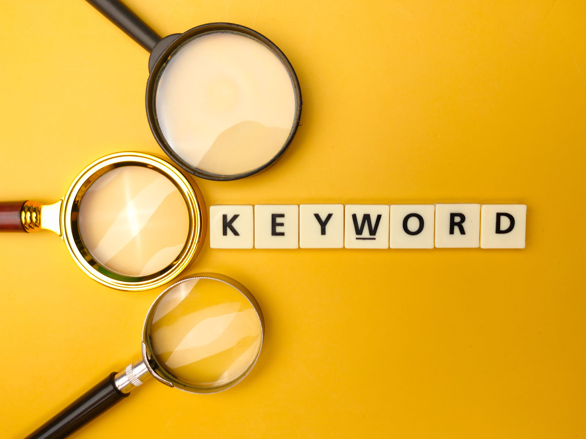 Magnifying glass and toys word with the word KEYWORD on yellow background