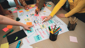 A dynamic teamwork scene depicting hands engaged in brainstorming and planning on a chart filled with colorful sticky notes and markers in a modern office setting.