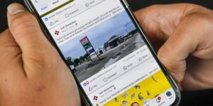 Close-up of a smartphone being held by two hands and showing a social media profile.