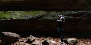 Image of a photographer taking a picture from inside of a cave.