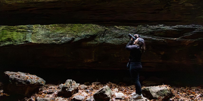 Image of a photographer taking a picture from inside of a cave.