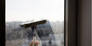 A squeegee cleans a dirty window, revealing a clean pane underneath.