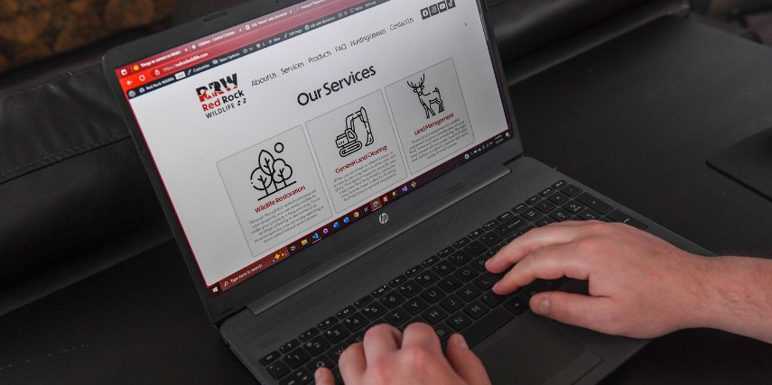 A person is using a laptop that shows the website design for Red Rock Wildlife, an SJC client.