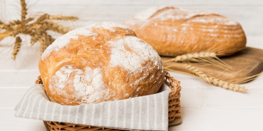 Two loaves of rustic bread shown in a basket and on a cutting board.